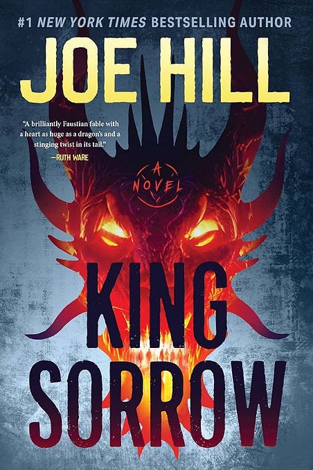 Fiery demon face with glowing eyes on a dark cover. Text: "Joe Hill, King Sorrow." Quote by Ruth Ware praising the novel. Fiery demon face with glowing eyes on a dark cover. Text: "Joe Hill, King Sorrow." Quote by Ruth Ware praising the novel.
