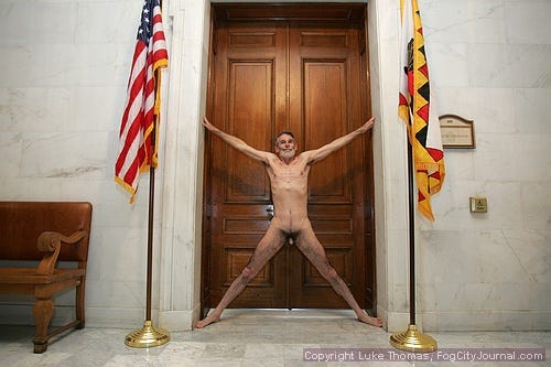 George Davis stands fully nude in a star-shaped pose between two flags inside San Francisco City Hall, smiling directly at the camera. George Davis stands fully nude in a star-shaped pose between two flags inside San Francisco City Hall, smiling directly at the camera.