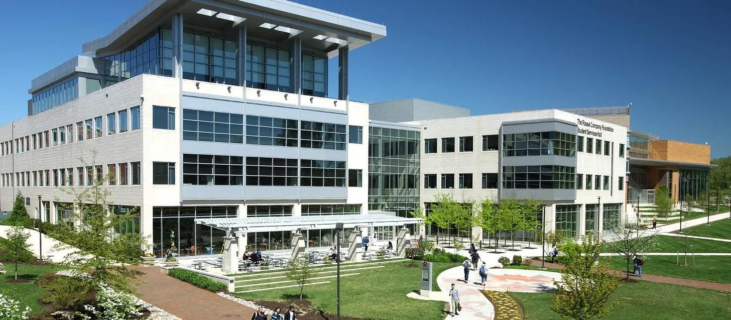 Exterior of The Rouse Company Foundation Student Services Hall at Howard Community College, with landscaped greenery and a clear blue sky.