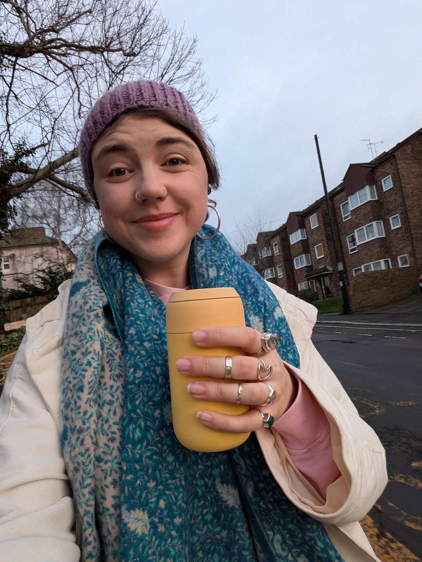 Grace's pale face bookmarked with a woollen hat and large bohemian print scarf, nose rings shining in the morning light, eyes watery in the cold, yellow Chilly's keep cup in hand as she walks down her road and into town. Grace's pale face bookmarked with a woollen hat and large bohemian print scarf, nose rings shining in the morning light, eyes watery in the cold, yellow Chilly's keep cup in hand as she walks down her road and into town.