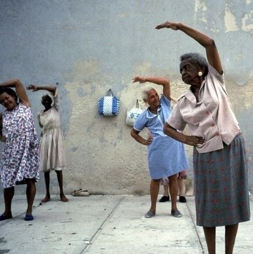 This may contain: an older woman is dancing on the sidewalk with other women standing around and looking at her