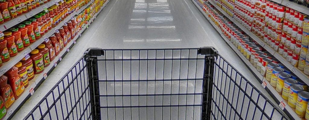 A grocery shopping cart in a supermarket corridor.