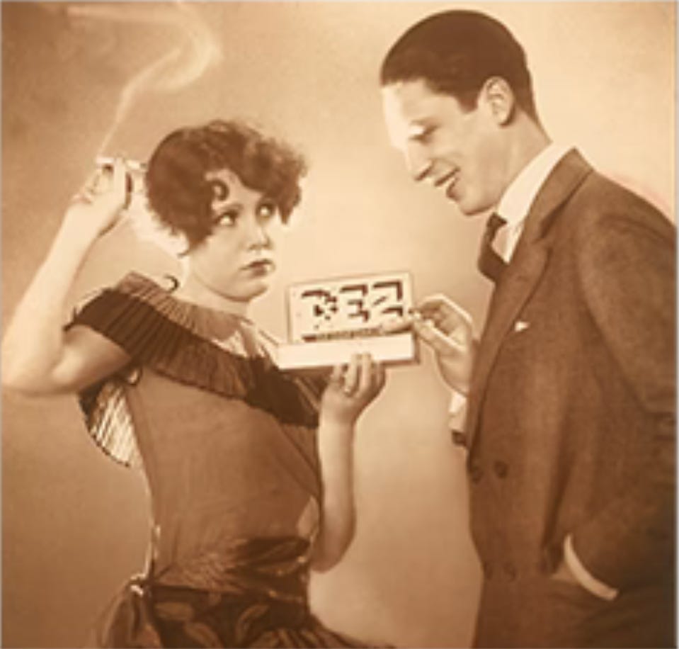 An attractive young woman takes away a man's cigarette and offers him a pack of PEZ mints.