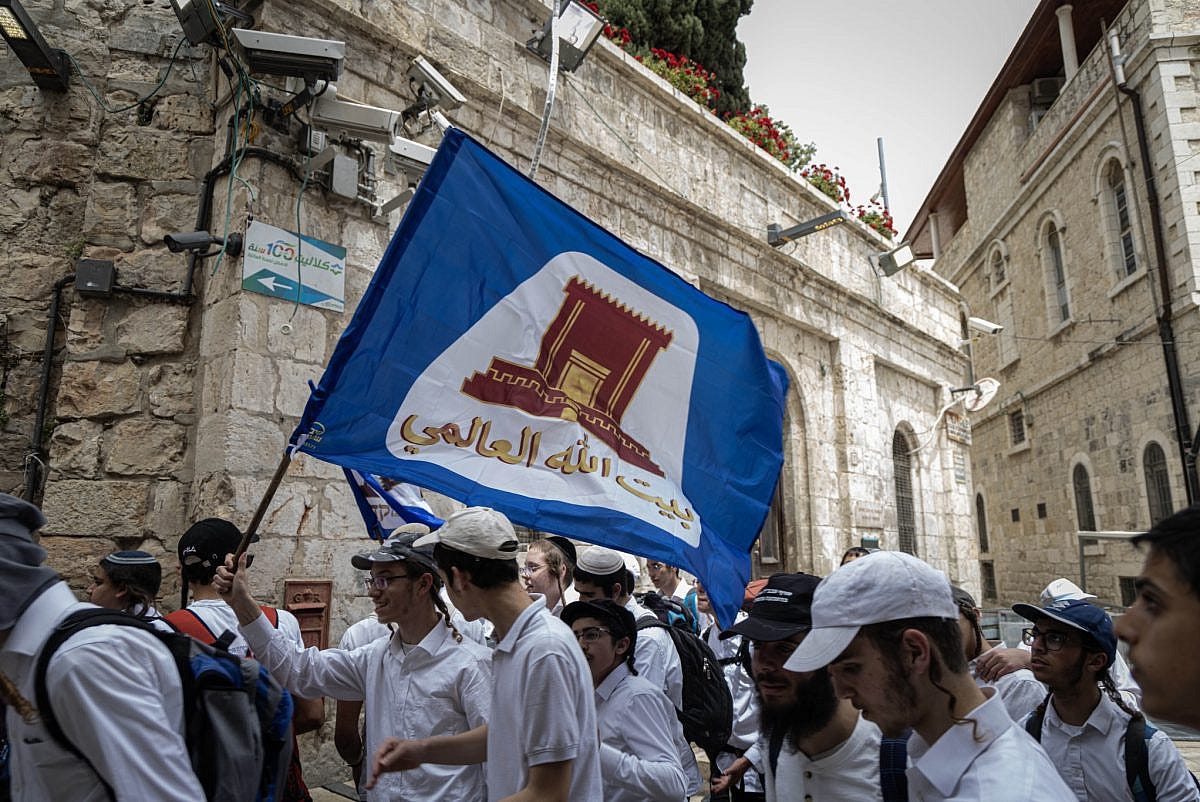 A participant in the Jerusalem Day Flag March carries a flag bearing the image of the Temple Mount, in Jerusalem's Old City, May 14, 2026. (Faiz Abu Rmeleh/Activestills) A participant in the Jerusalem Day Flag March carries a flag bearing the image of the Temple Mount, in Jerusalem's Old City, May 14, 2026. (Faiz Abu Rmeleh/Activestills)