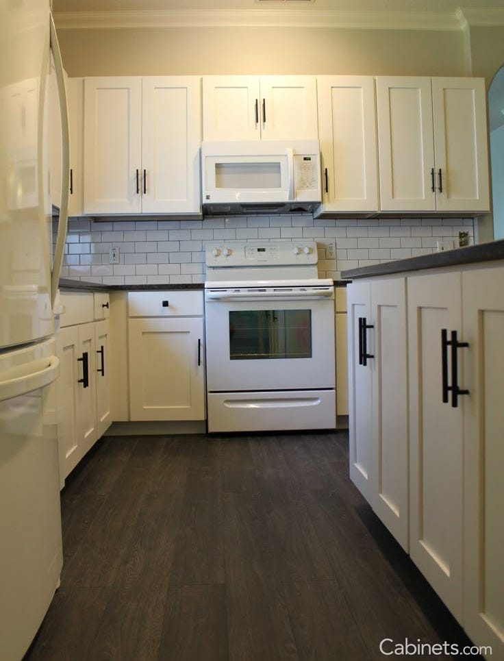 This may contain: an empty kitchen with white cabinets and appliances