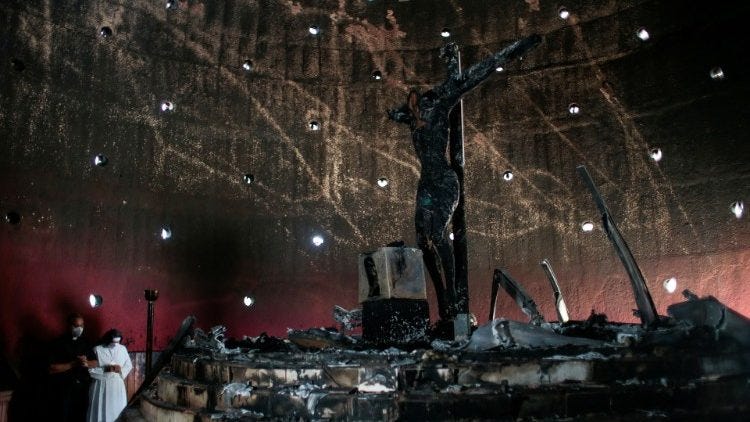 A priest and a nun pray before the burned crucifix in Managua's cathedral A priest and a nun pray before the burned crucifix in Managua's cathedral