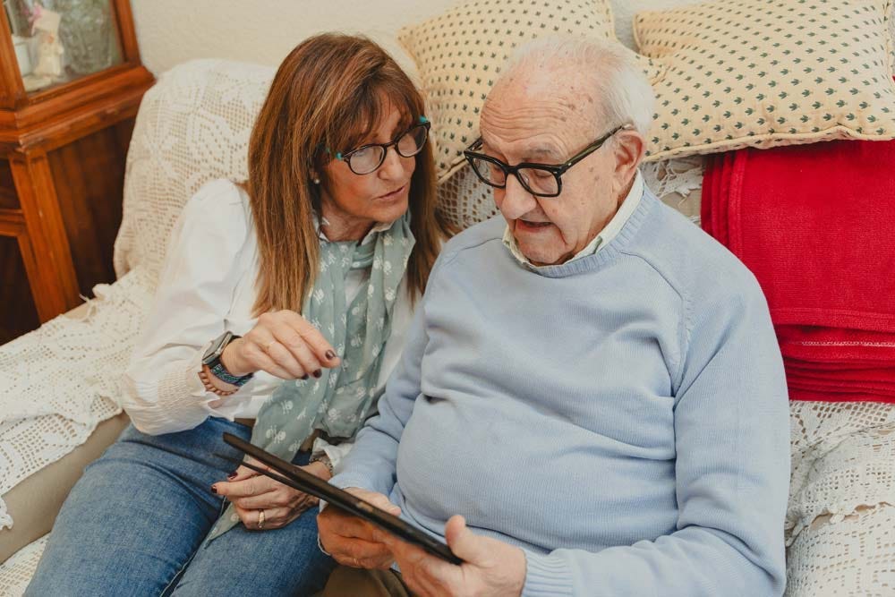 Adult daughter showing elderly father how to use digital tablet.