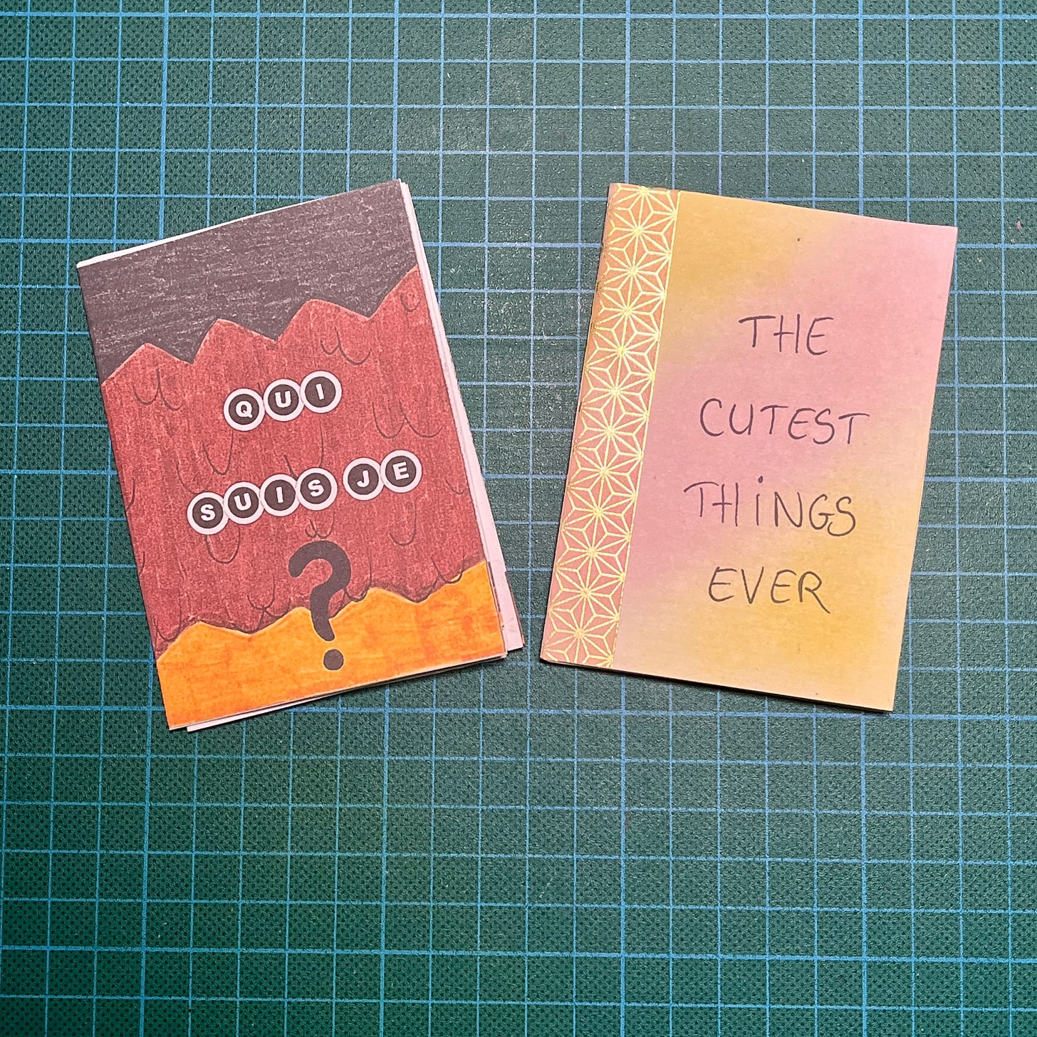 Photo des deux mini zines posés sur mon tapis de découpe. L'un s'appelle Qui suis-je et l'autre The cutest things ever.