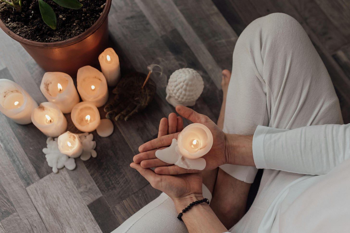 A Person Sitting with Crossed Legs Holding White Lighted Candle