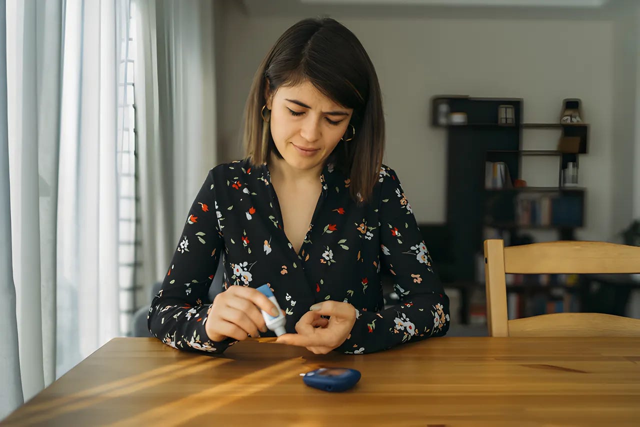 Woman using a blood ketone meter at her kitchen table. Woman using a blood ketone meter at her kitchen table.