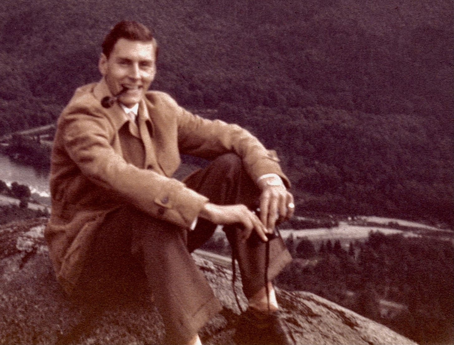 man smoking a pipe sitting on a rock