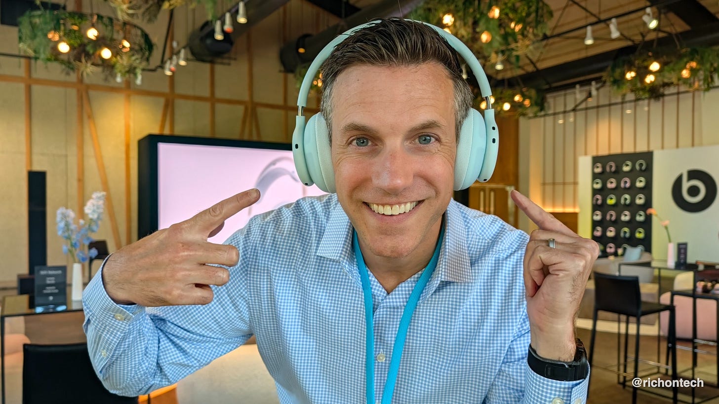 Rich DeMuro smiles and points to a pair of light blue Beats 360 over-ear headphones while testing them at a Beats event.