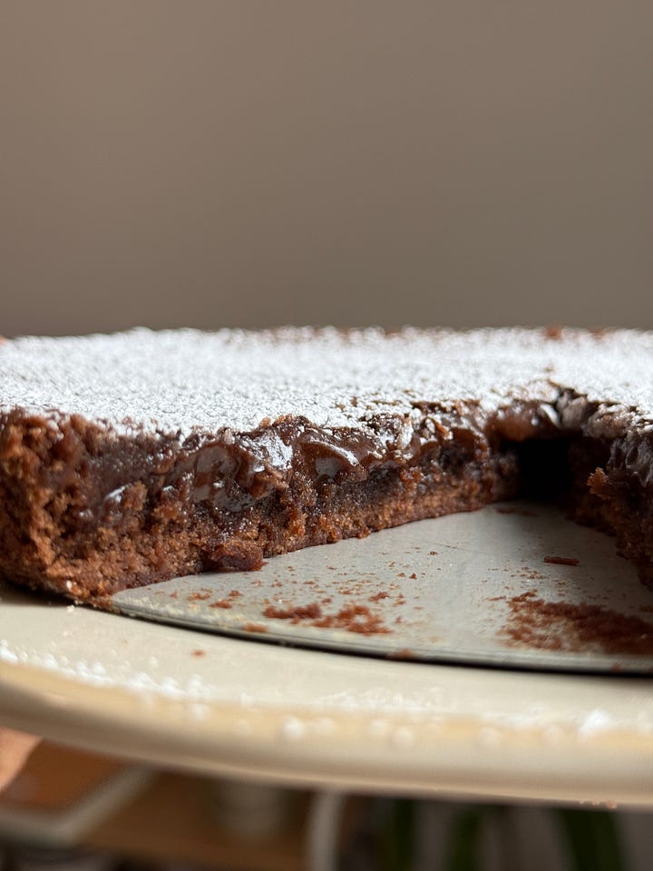 a kladdkaka with a slice on a plate next to a bowl of whipped cream