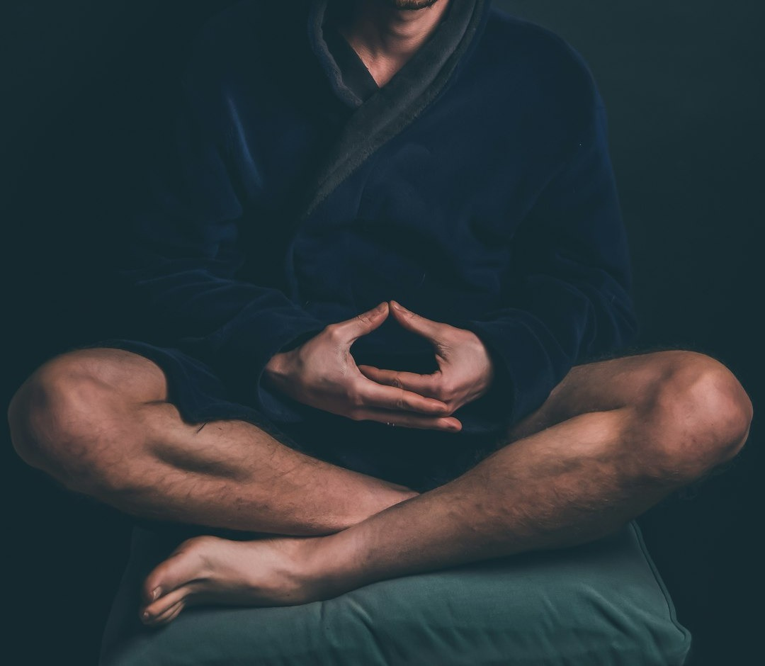 man in black hoodie sitting on black background man in black hoodie sitting on black background