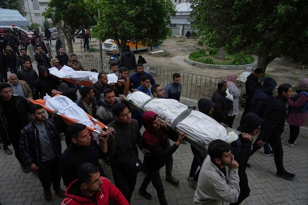 Mourners carry the bodies of Palestinians including children who were killed by an Israeli army airstrike, at the Baptist Hospital in Gaza city, Friday, March 21, 2025 (AP)