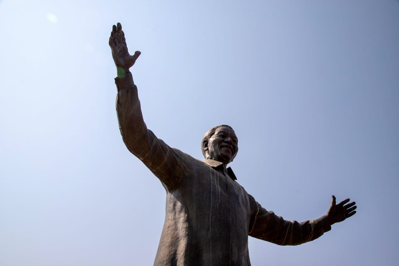 The bronze statue of Nelson Mandela at the Union Buildings in Pretoria, photographed from below against a pale sky, arms outstretched. The bronze statue of Nelson Mandela at the Union Buildings in Pretoria, photographed from below against a pale sky, arms outstretched.