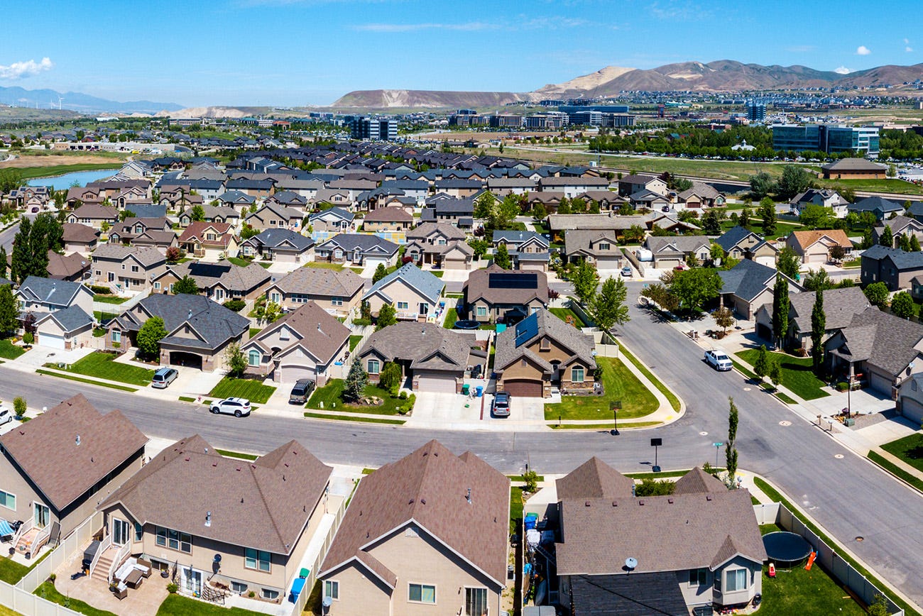Aerial view of a suburban neighborhood block with twenty homes, illustrating the community-level impact of workforce displacement and long-term unemployment.