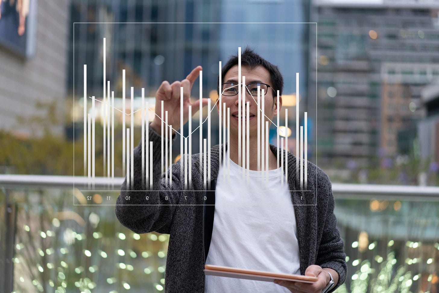 Man arranging bars on a bar chart on a transparent glass screen.