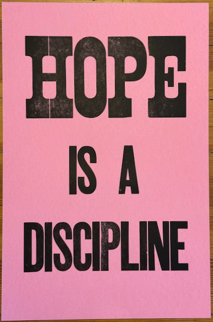 "HOPE IS A DISCIPLINE" printed with large wood type in black on pink paper "HOPE IS A DISCIPLINE" printed with large wood type in black on pink paper