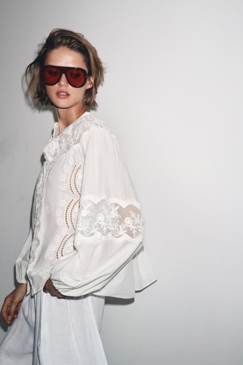 "White shirt set with floral embroidery and long puffed sleeves, round neck, and button closure."