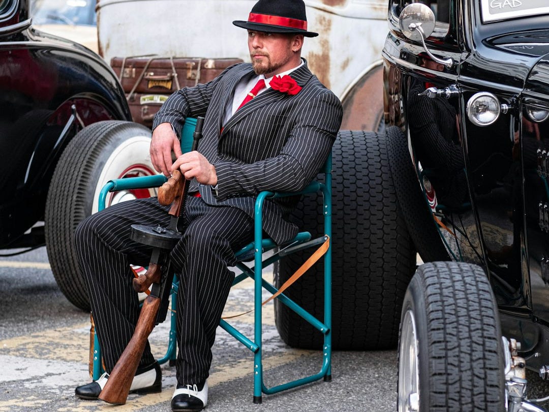A man sitting in a chair next to a black car