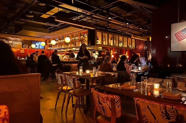 A dark, red-cast, moody dining room.