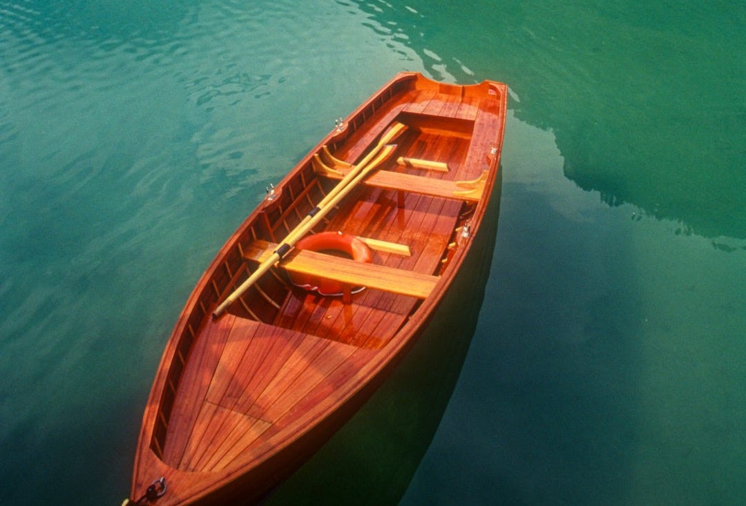 brown wooden boat on body of water during daytime brown wooden boat on body of water during daytime