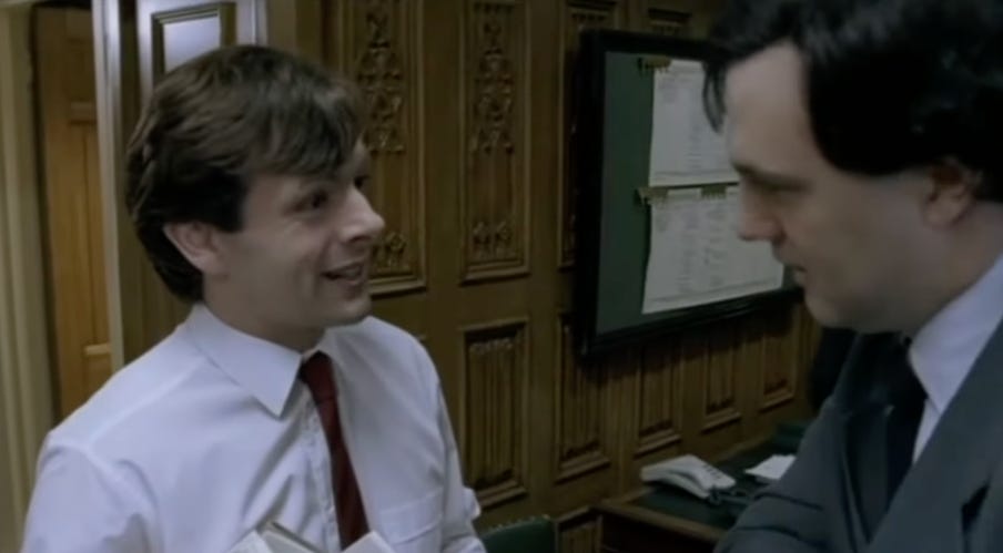 A person in a white shirt and red tie talking to another person

Description automatically generated