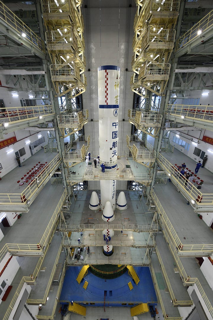 An assembled Long March 2F/G in (left) and a Shenzhou spacecaft under a protective cover (right) at the Jiuquan Satellite Launch Center.