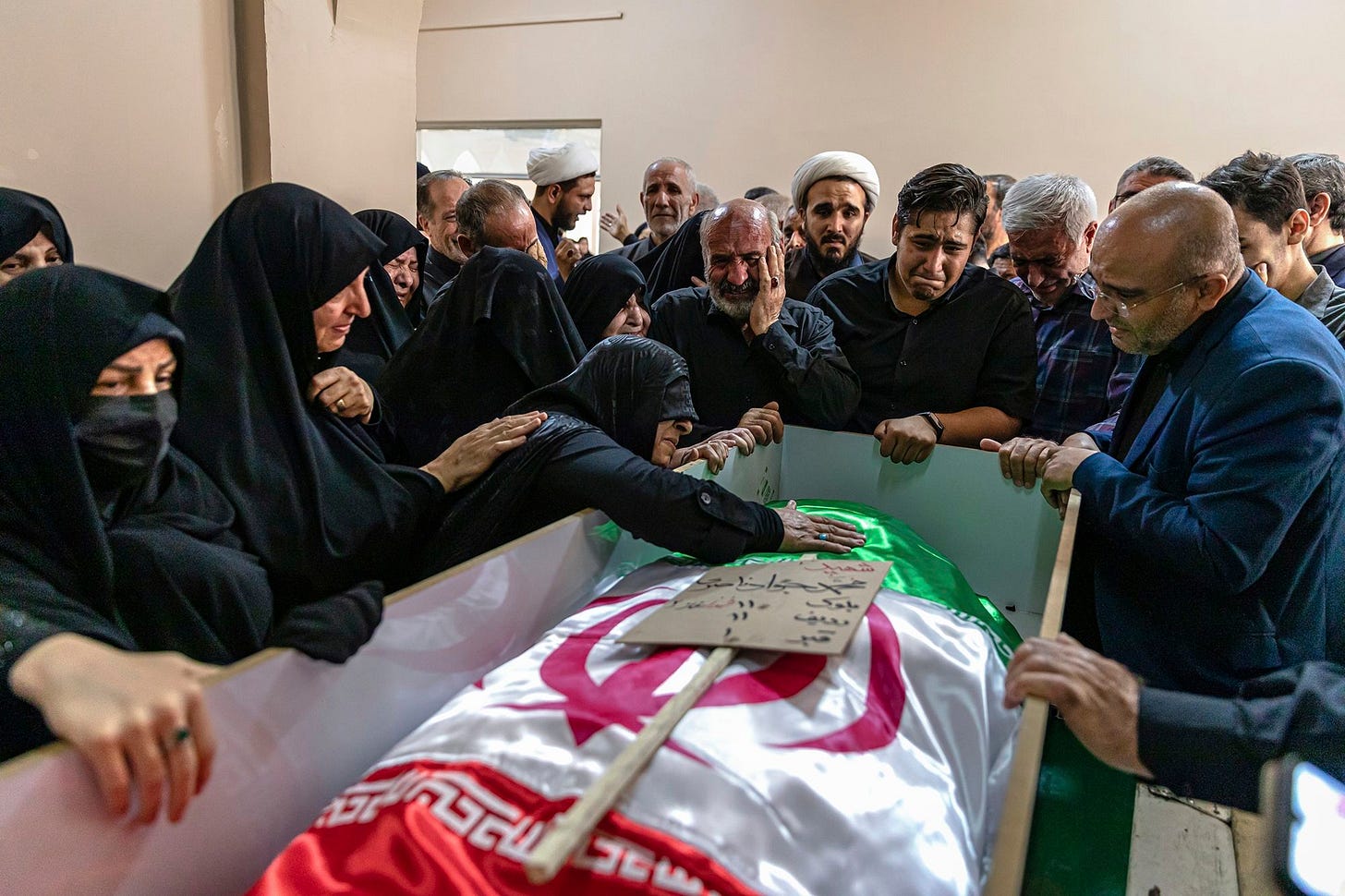 A mourner touches the shrouded body of a loved one who was killed in Israeli strikes in the Iranian city of Tabriz on Monday.
