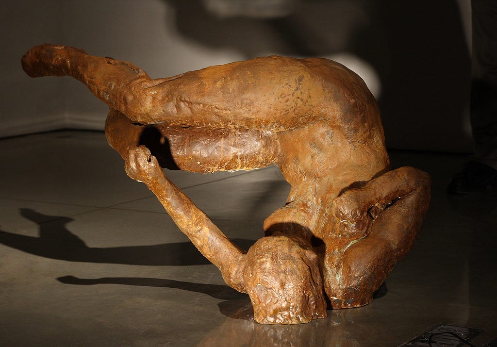 A bronze sculpture of a woman tumbling through darkness.