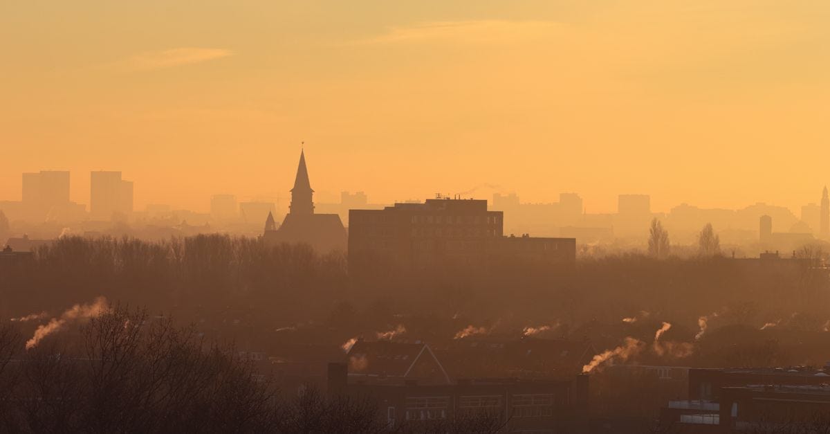 Photo: Bráulio jardim / Pexels Silhouetted city skyline with mist and smoke at sunset creating a moody atmosphere.