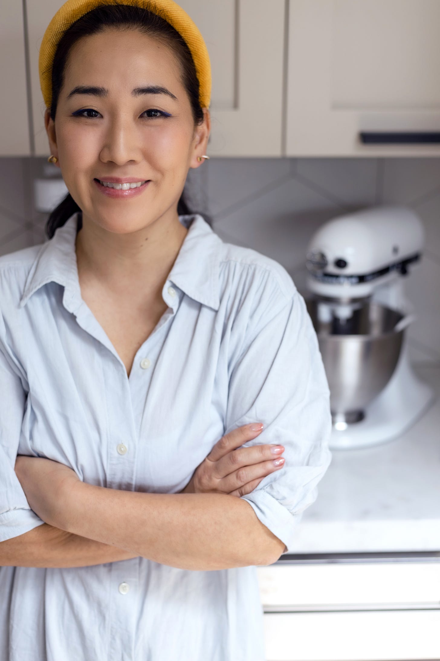 Jane Nicholson standing in her kitchen in a polo shirt and yellow headband Jane Nicholson standing in her kitchen in a polo shirt and yellow headband