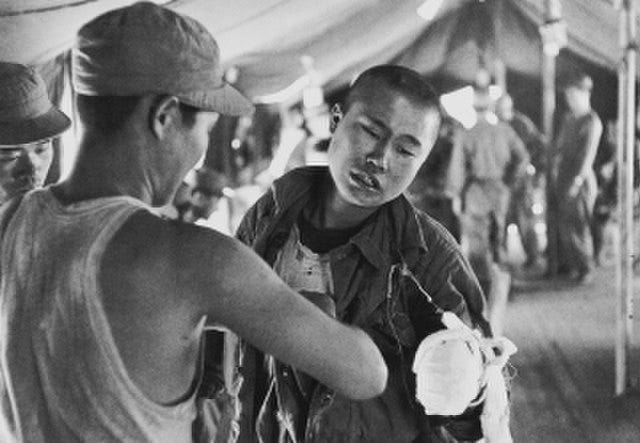 “There was a field hospital with a tent near the “Iron Triangle”. First aid for the wounded soldiers is given, and the wounded soldiers are sent to the hospital further back. The Korean soldier, who lost his left wrist, desperately endured the pain while being treated by a medic. The soldier, who still retains the vestiges of a boy, was just in the middle of a cannonball.”