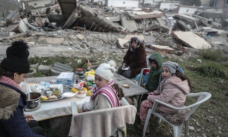 A family have their breakfast near a collapsed building in Hatay.