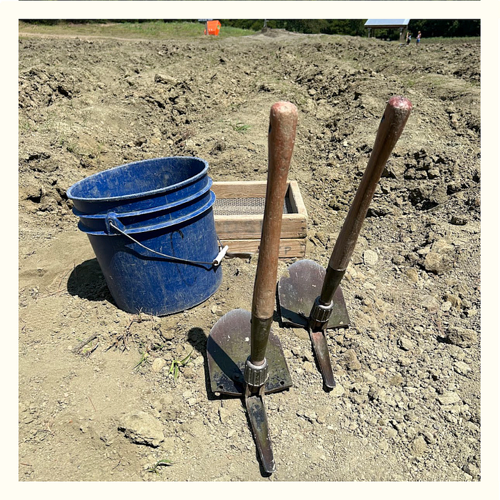 At left, an image of a crisp, sunny day with no clouds in the sky, above a well-turned field with no vegetation and deep ruts for diamond digging. At right, a blue five-gallon bucket, two shovels, and a wooden sifting box.
