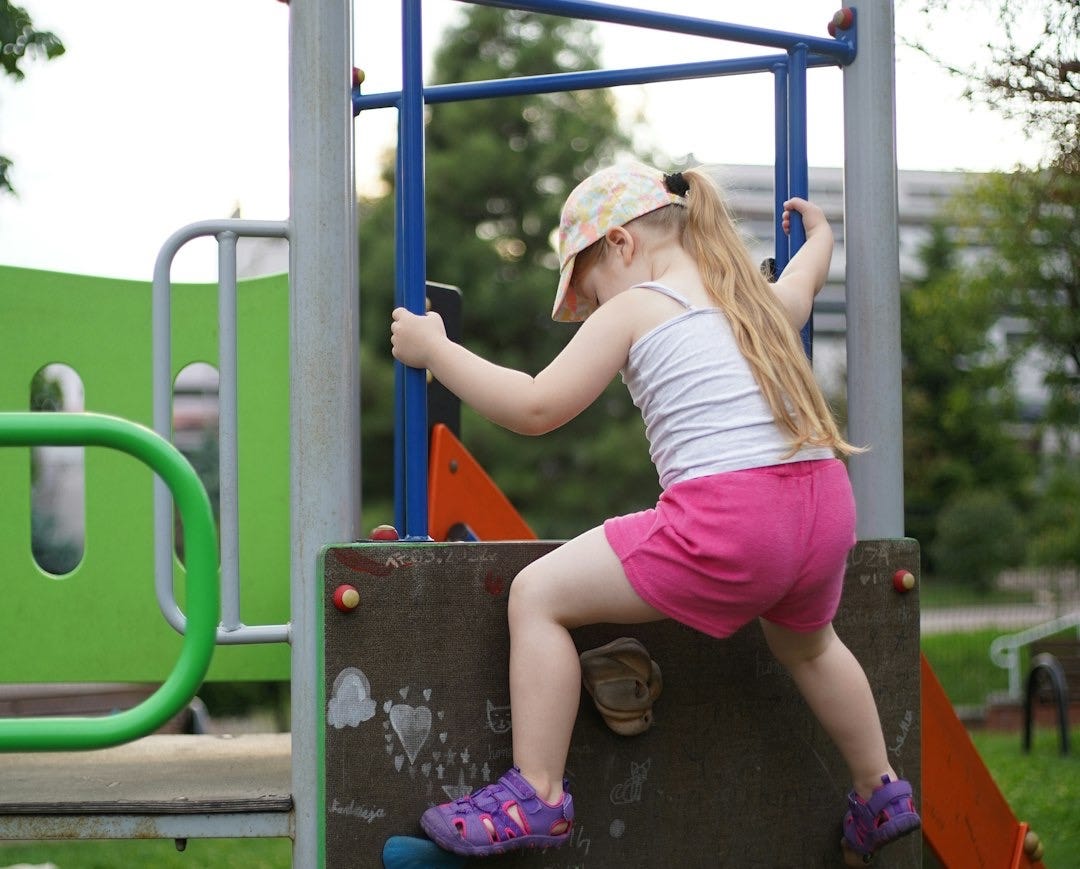 a little girl climbing on a climbing wall