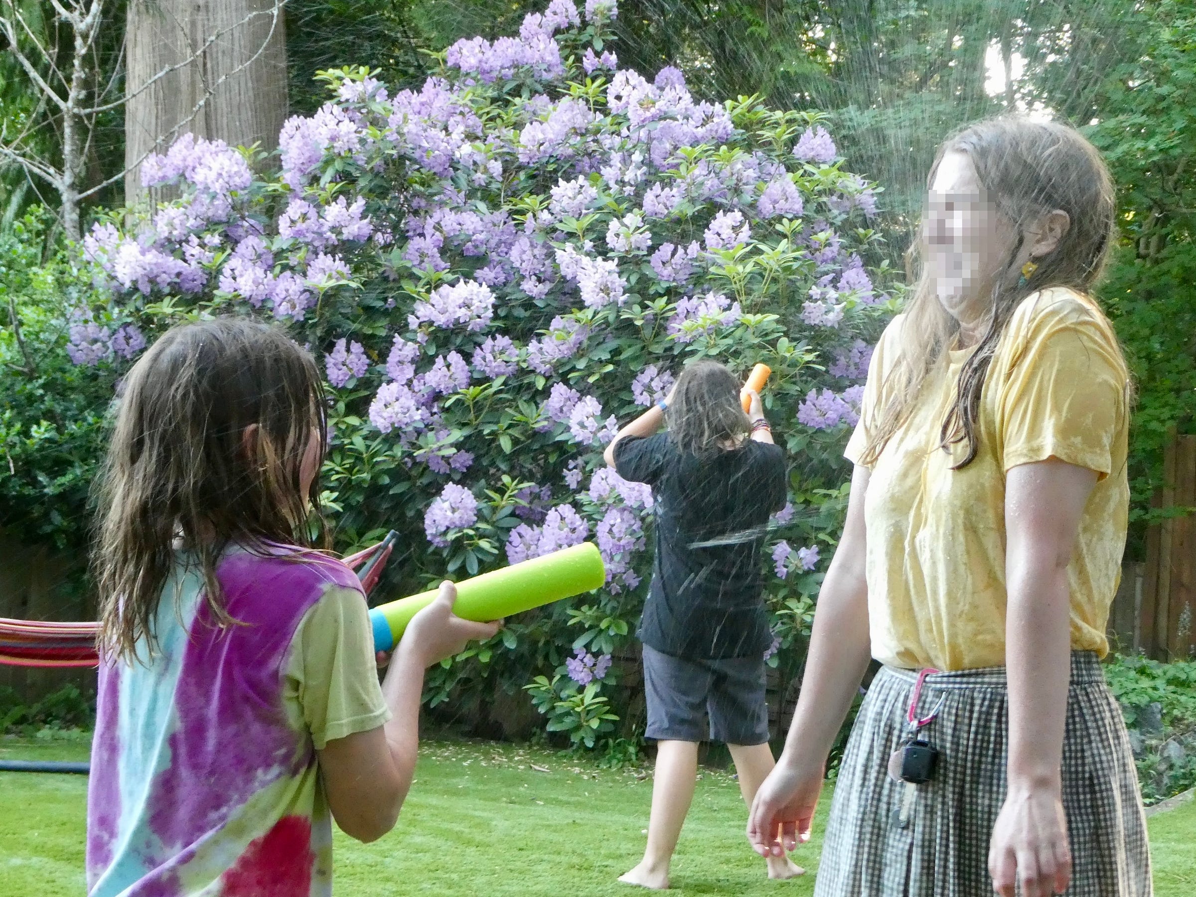 Girl spraying water in woman's face with water gun.