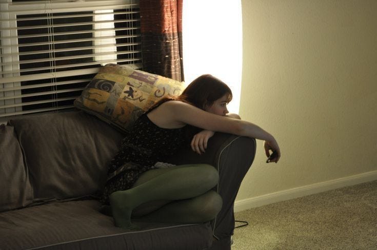 This may contain: a woman sitting on top of a couch next to a window