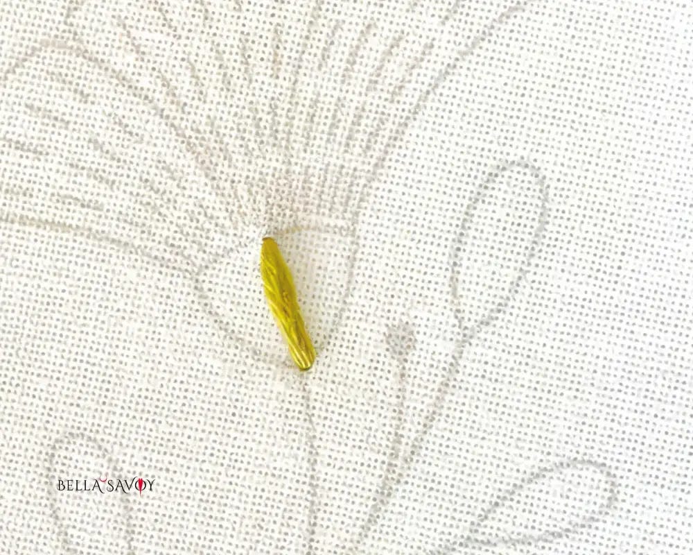 single green seed stitch placed in the center of a flower receptacle template to divide space for the satin stitch