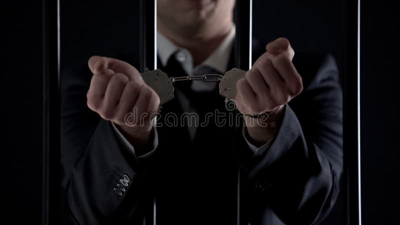 Man in suit showing hands in handcuffs behind bars, bribery, financial fraud, stock photo. Man behind bars suit stock images, royalty-free photos and pictures