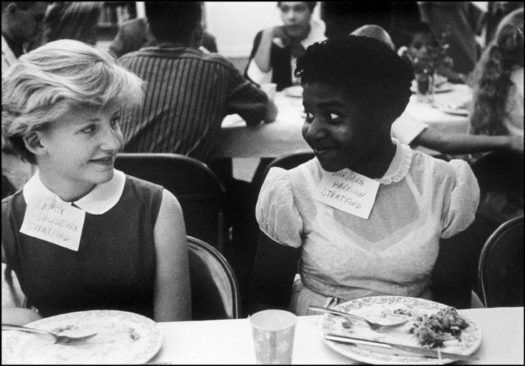 This may contain: two women sitting at a table with plates of food
