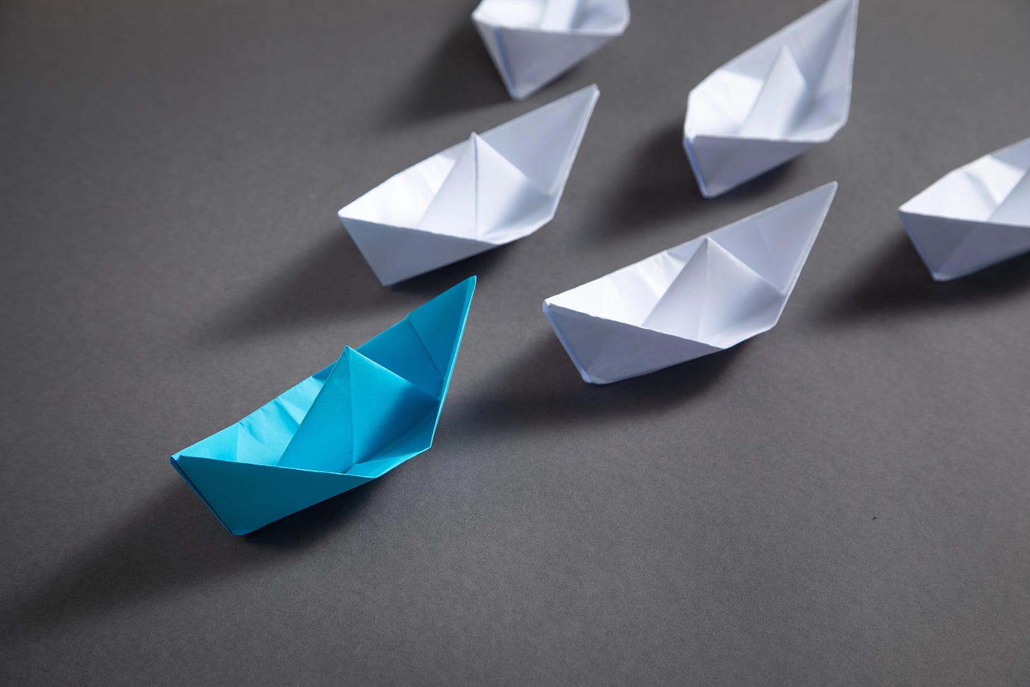A graphic representing leadership with a blue boat in front of white boats