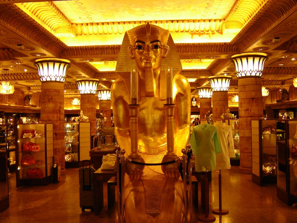 The Egyptian themed Room of Luxury 4 at Harrods, London, in 2006. In the centre a huge sphinx stares at the viewer. It is surrounded by Egyptian-style columns, between which are display cases and mannekins. The entire room is gold. Photograph: Targerman, via Wikipedia