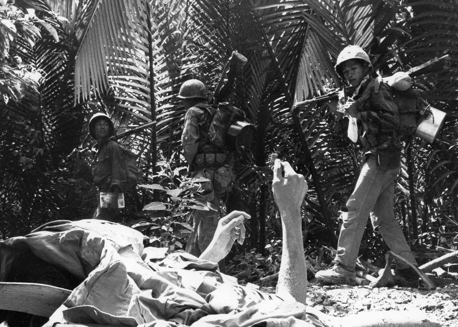 A dying Viet Cong guerrilla, partially covered, raises his hands as South Vietnamese Marines conduct a search operation in palm groves near Long Binh, Mekong Delta, February 27, 1964, following a fierce engagement. A dying Viet Cong guerrilla, partially covered, raises his hands as South Vietnamese Marines conduct a search operation in palm groves near Long Binh, Mekong Delta, February 27, 1964, following a fierce engagement.