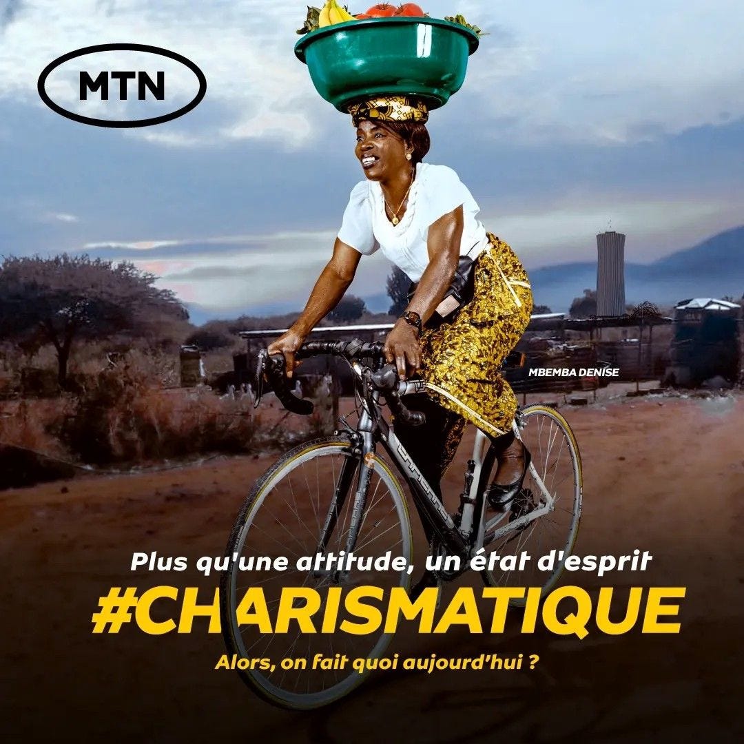 Femme congolaise sur un vélo de course transportant un panier plein de fruits sur sa tête.