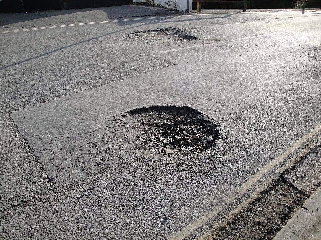 City streets with large rough pothole.
