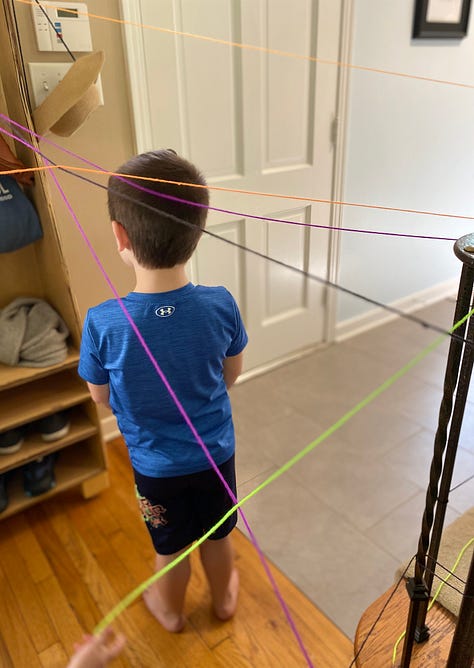 Yarn strung up through a house, a child stands in the middle of the yarn