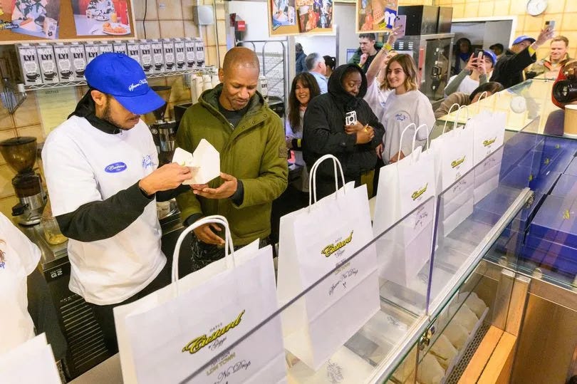 Giggs handing out cake and custard inside the bakery