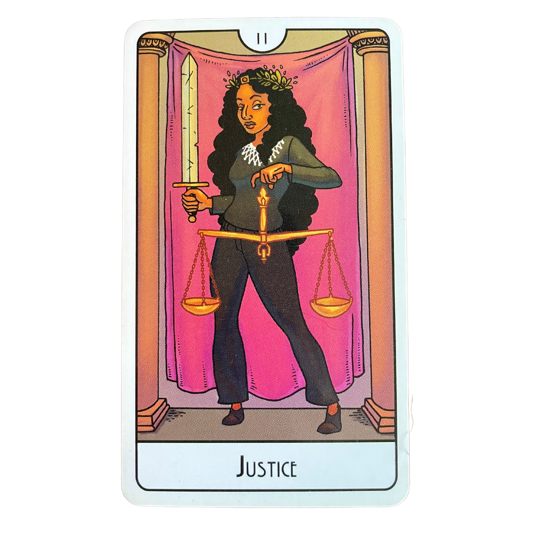 This Might Hurt Tarot Justice card, a fierce figure with ling dark hair holds a sword and scales